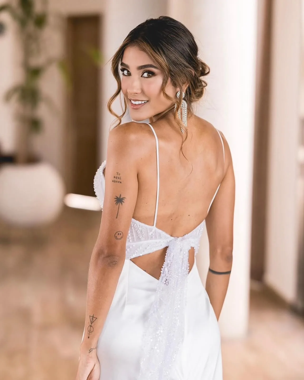 Novia con vestido de espalda descubierta, mirando por encima del hombro en un pasillo interior
