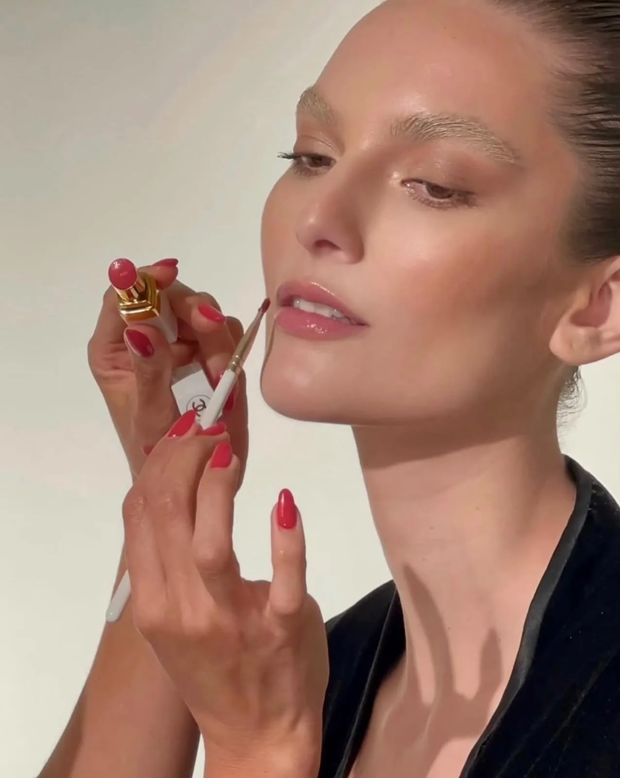 Primer plano de aplicación de labial rojo con pincel, manicura a juego