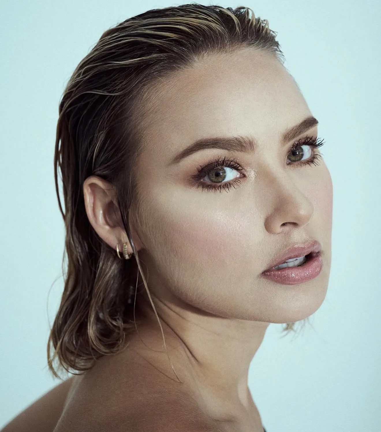 Retrato de belleza con piel luminosa y cabello húmedo peinado hacia atrás