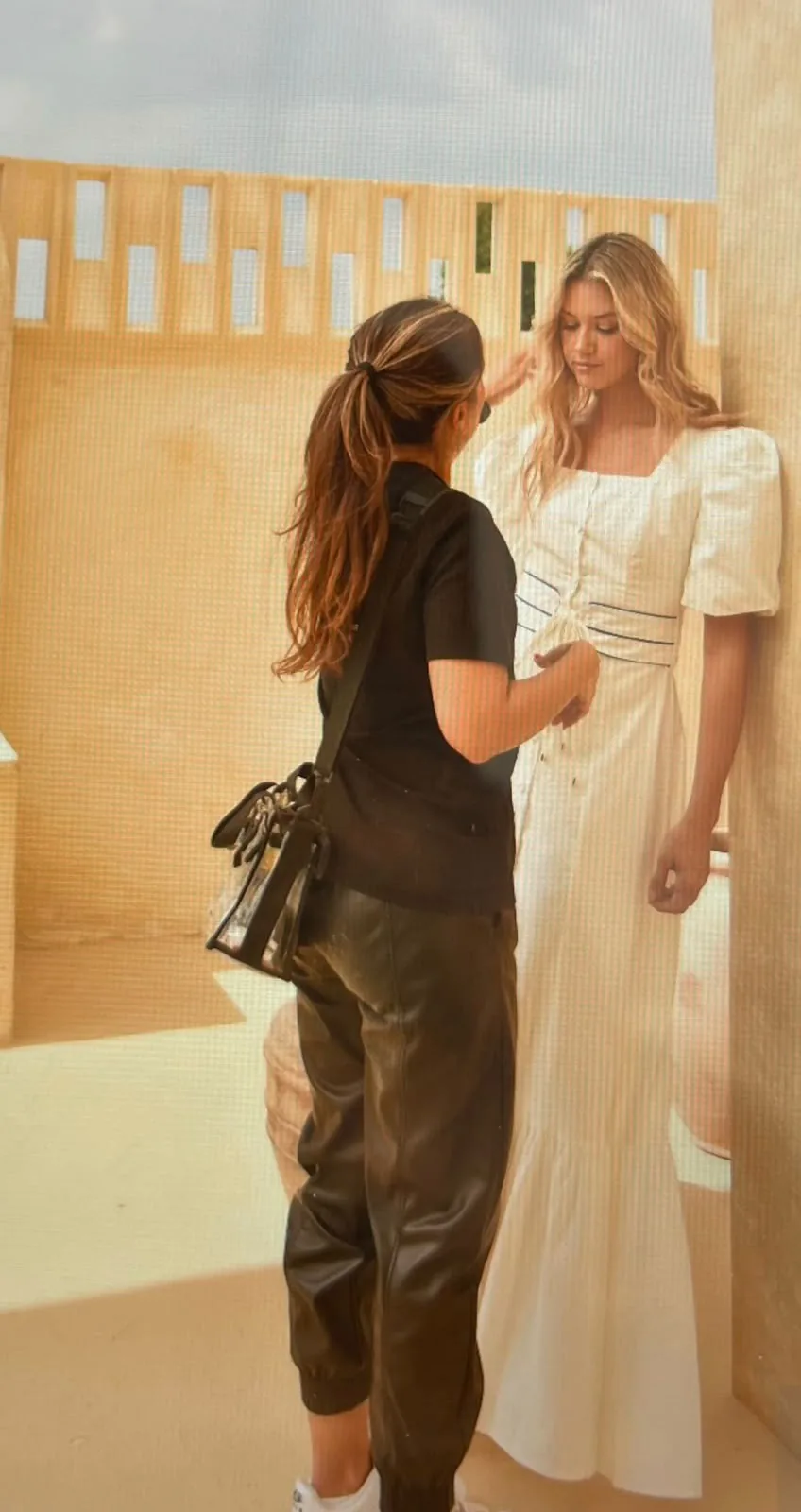 Retoque de maquillaje a la modelo durante el rodaje, en un set de tonos arena